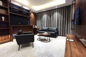 Una sala de estar moderna con sofá, sillón, mesa de centro y estanterías empotradas.