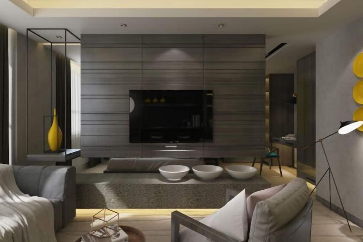 Una sala de estar moderna con un televisor de pantalla plana, sofás grises, una mesa de centro y un jarrón decorativo.