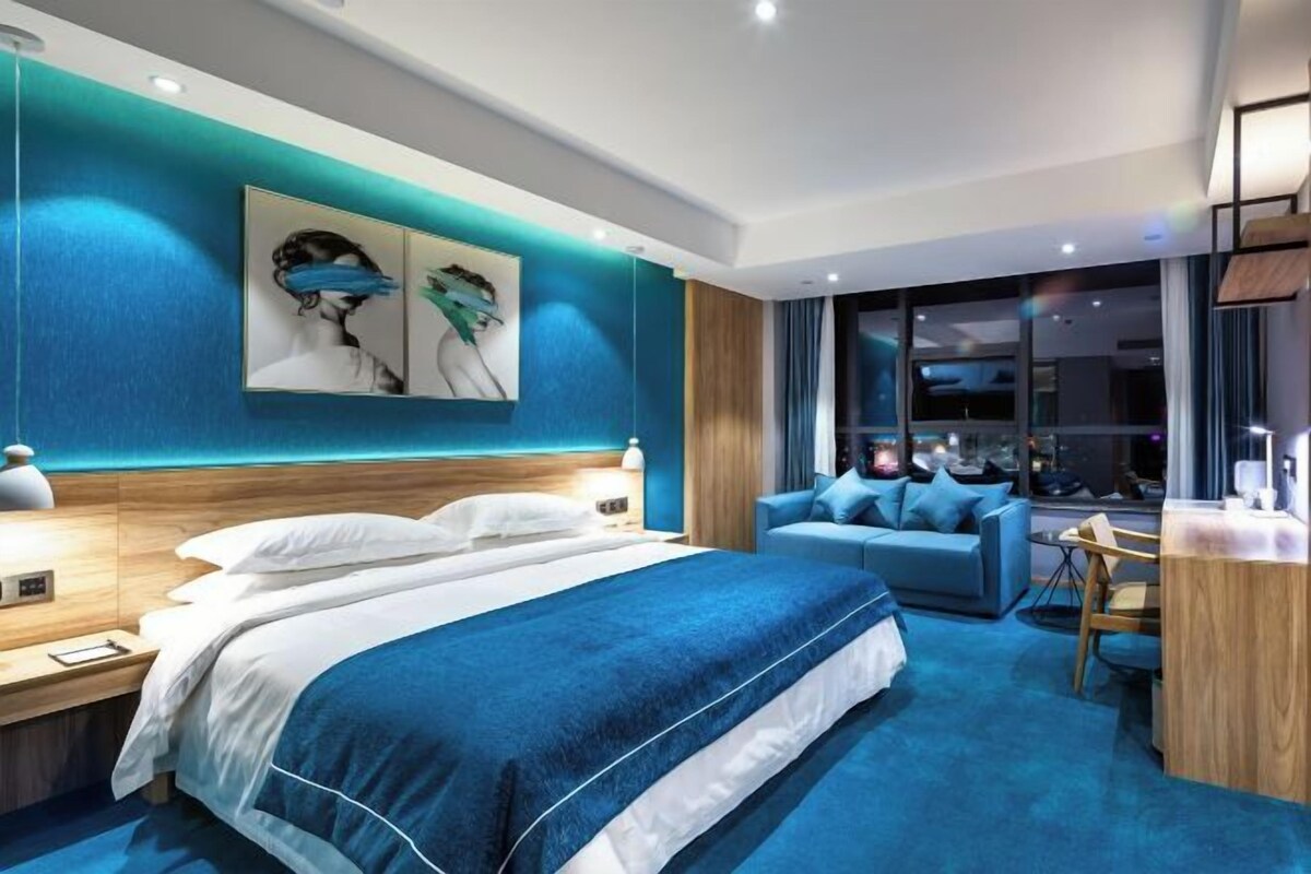 A modern hotel room with a large bed, a seating area, and a desk.