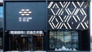 Un bâtiment moderne à la façade géométrique, doté d’un logo bien visible et d’une enseigne indiquant qu’il abrite une entreprise liée aux arts et à la culture.