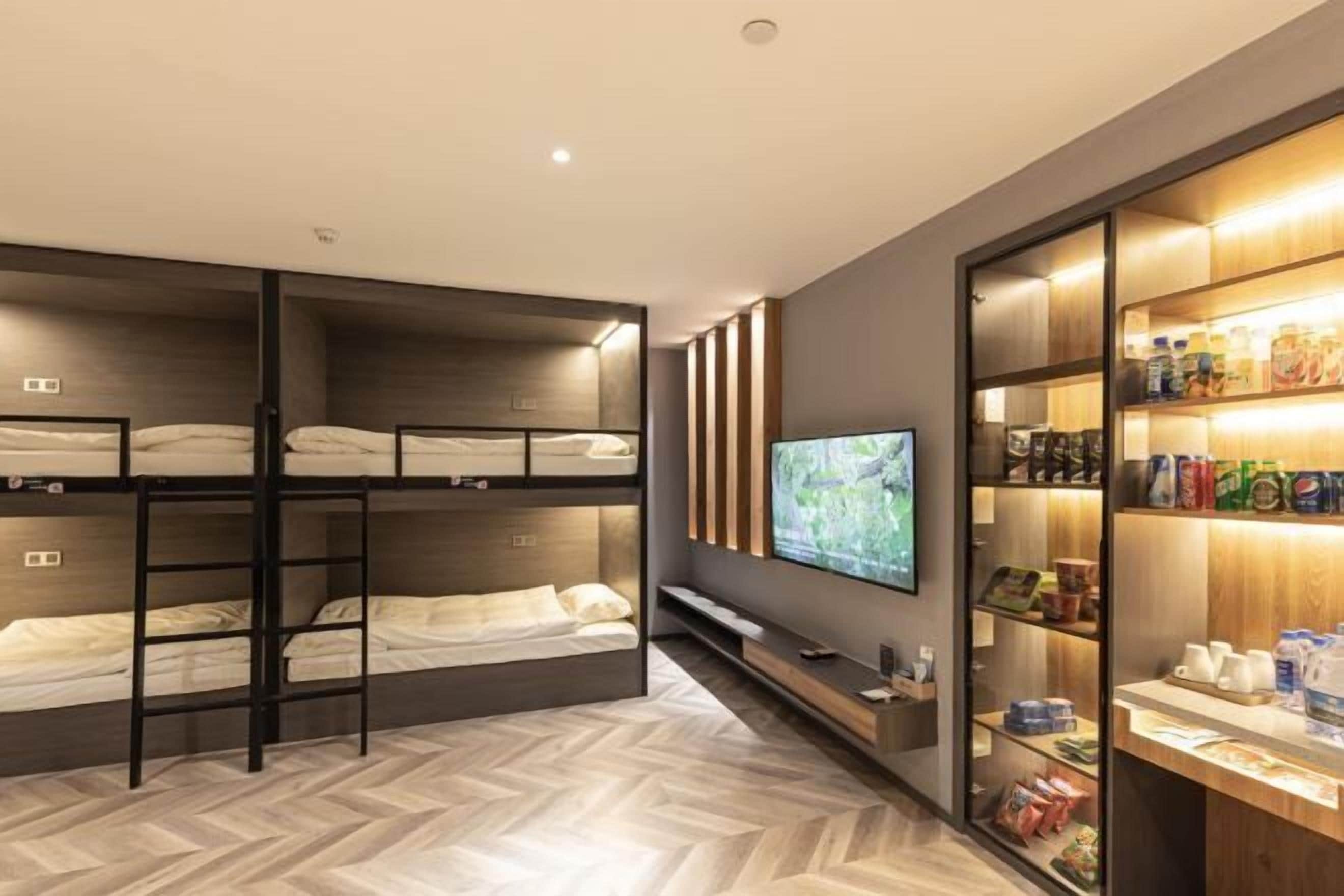 A hotel room with bunk beds, a TV, and a minibar.