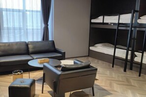 A modern hotel room with a sofa, a small round table, a chair, a bunk bed, and a window with curtains. - Yunyi Art Hotel (Rizhao)