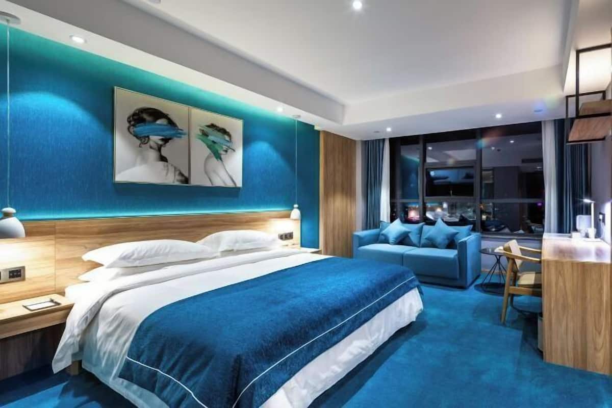 Una habitación de hotel moderna con una cama grande, un área de descanso y un escritorio.