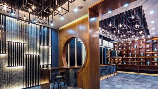 Un intérieur moderne comprenant un bar, un mur décoratif et une étagère ornée de vases.