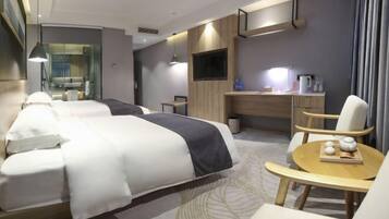 A modern hotel room with a large bed, a desk, a chair, and a small table with decorative items.