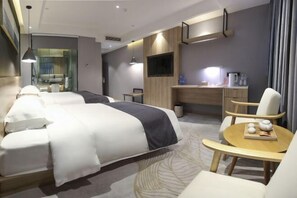 A modern hotel room with a large bed, a desk, a chair, and a small table with decorative items.