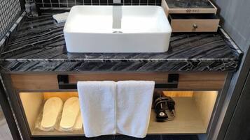 A bathroom with a white sink, a wooden vanity, and a towel rack holding two towels.