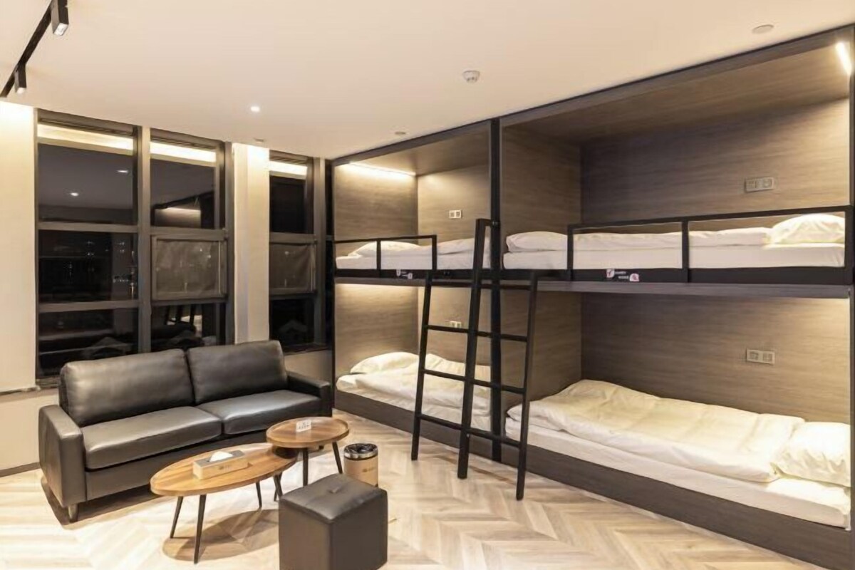 A modern hotel room with a sofa, a coffee table, and bunk beds.