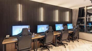 A modern office with four desks, each with a computer monitor, ergonomic chairs, and a wooden desk.