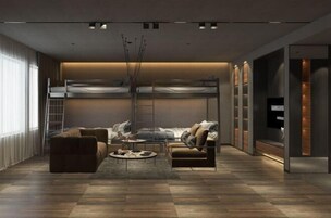Una sala de estar moderna con sofá, sillón y mesa de centro. Se ve una litera al fondo y un televisor en la pared derecha.
