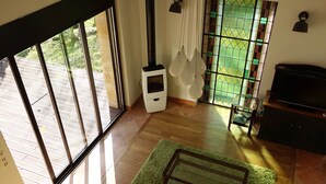 A room with a large sliding glass door, a fireplace, a green rug, and a television. - Quiet house with large garden and pool, in the Entre-deux-Mers (Saint-Vincent-de-Pertignas)