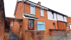 A two-story brick house with a front door, a small porch, and a gated driveway. - Berlin Town house Belfast (Belfast)