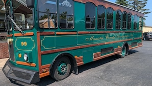 Un autobús verde y marrón antiguo con el texto "Manistee County Transportation, Inc." estacionado en un estacionamiento.