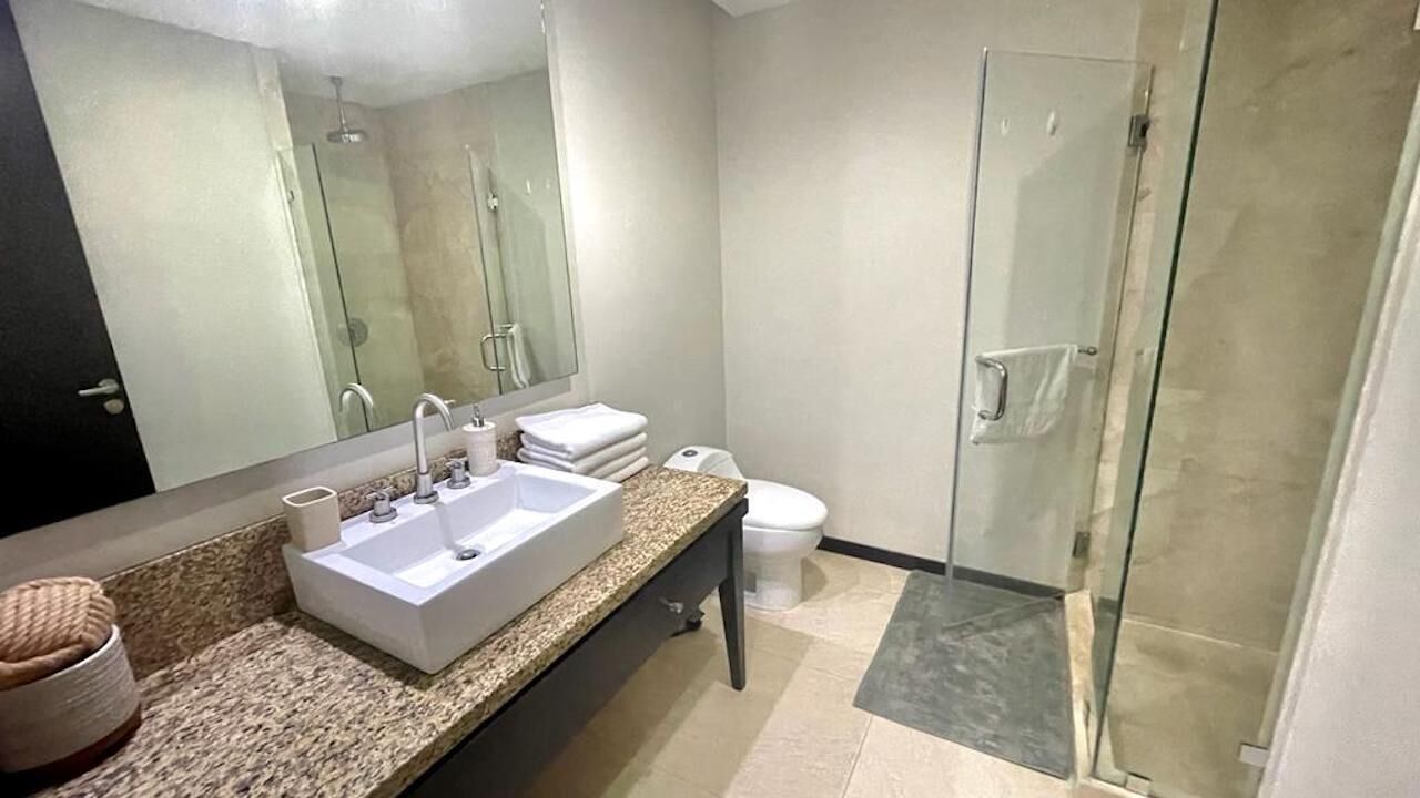 Et moderne badeværelse med en stor vask, toilet og brusekabine i glas.