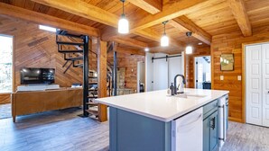 A modern kitchen with a central island, wooden ceiling beams, and a built-in TV. - Base Camp (Davis)