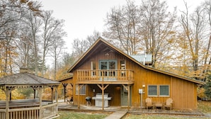 A wooden cabin with a balcony, a covered deck, and a barbecue area. - Base Camp (Davis)