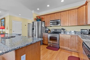 Enjoy cooking in this well-equipped kitchen with a granite countertop, stainless steel appliances, and wooden cabinetry.