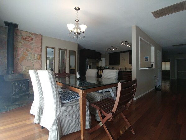A dining area with a glass-top table, checkered chairs, and a chandelier.