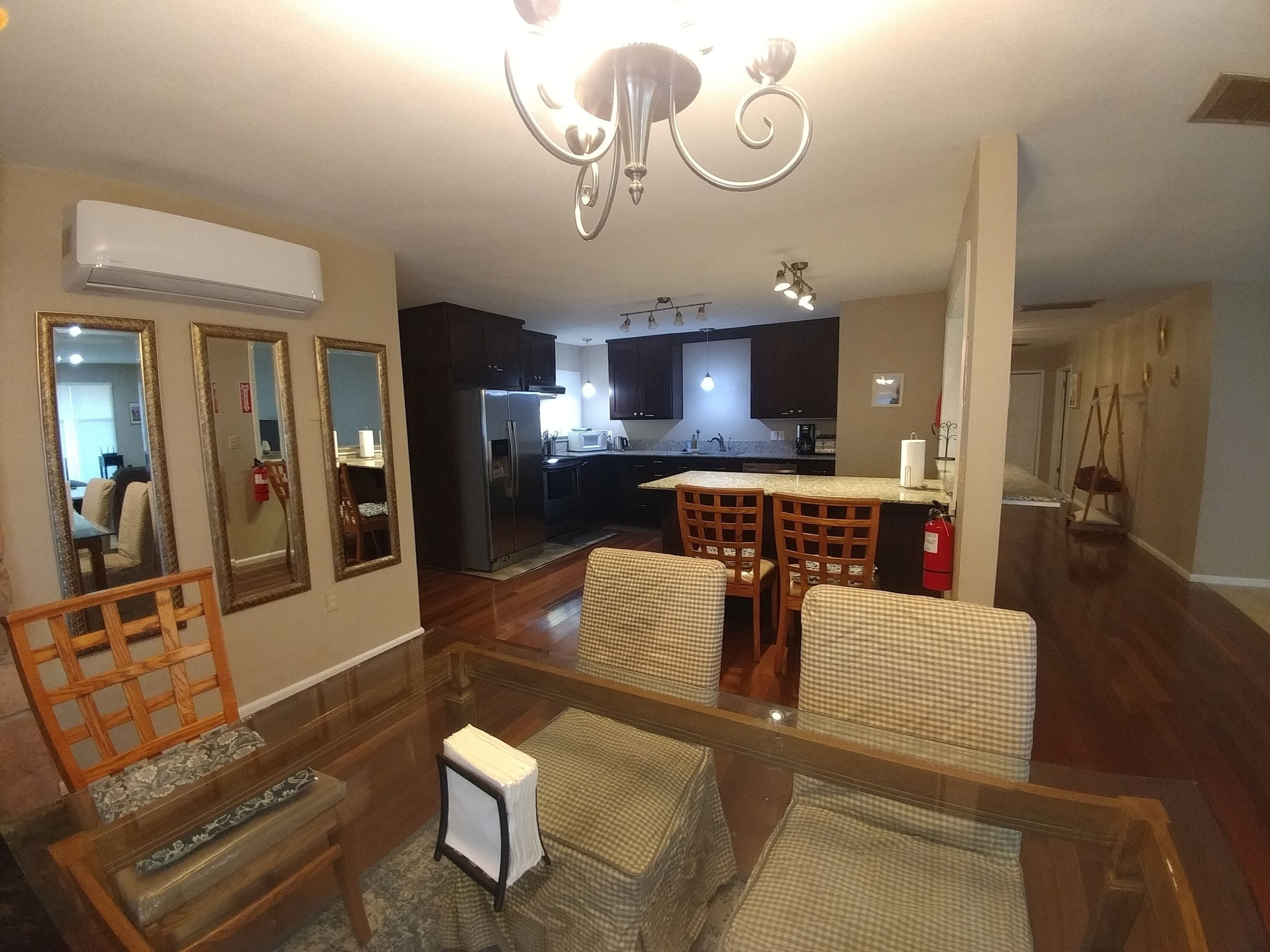 A spacious living room with a dining area, a kitchen in the background, and a staircase leading to another level.