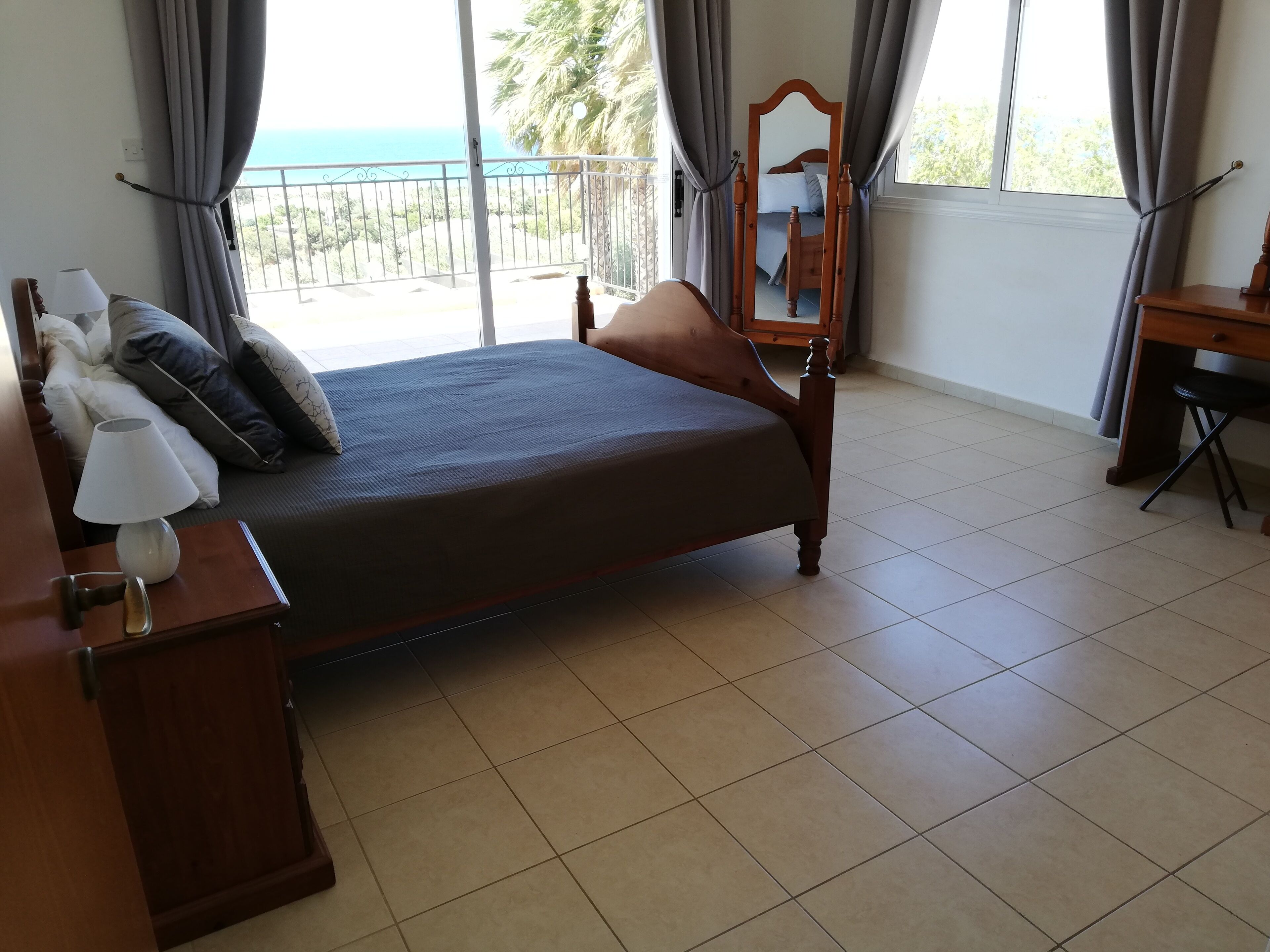 Ein Hotelzimmer mit Bett, Schreibtisch, Stuhl, Lampe und Meerblick durch große Fenster.