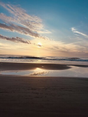 Una playa con mar tranquilo y un atardecer.