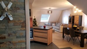 Un espacio de sala acogedor con una mesa de comedor de madera, una pequeña cocina y una zona de estar confortable.