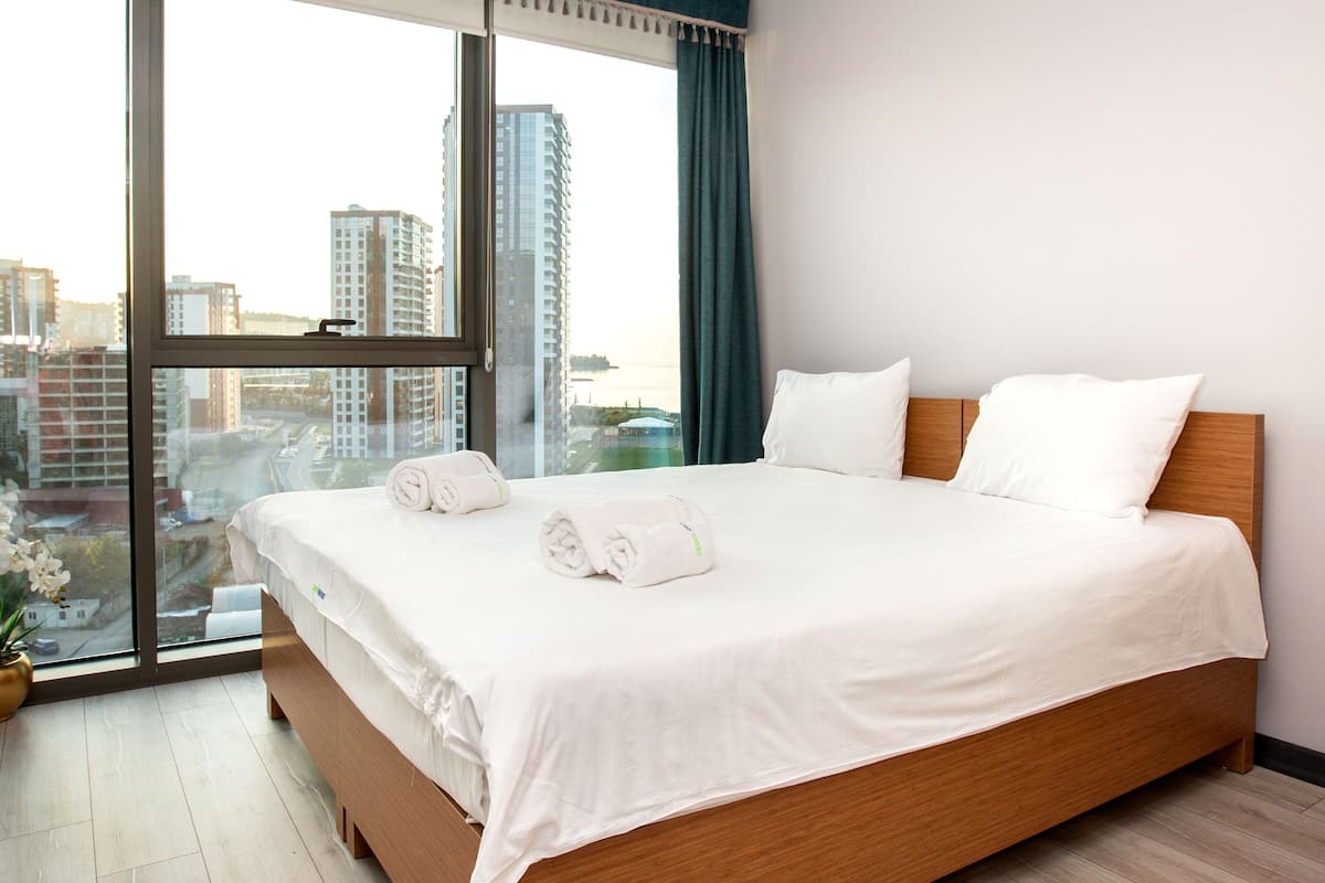Un moderno cuarto de hotel con una cama grande, vistas de la ciudad y un amplio ventanal.