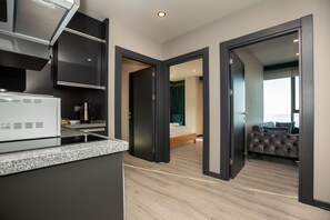 Een moderne hotelkamer met een kitchenette, een bed en een zithoek.