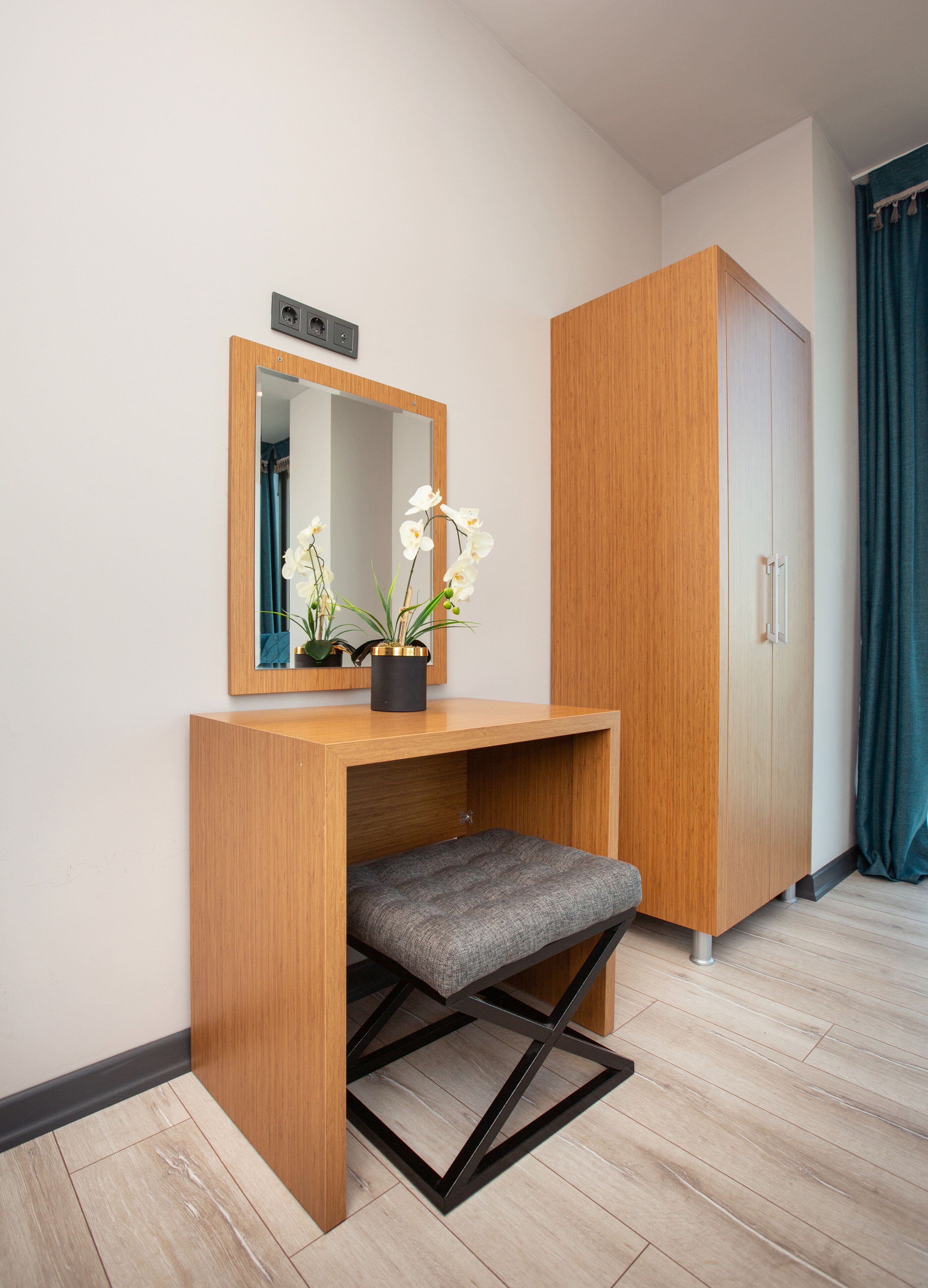 A wooden desk with a mirror, a bench, and a potted orchid.
