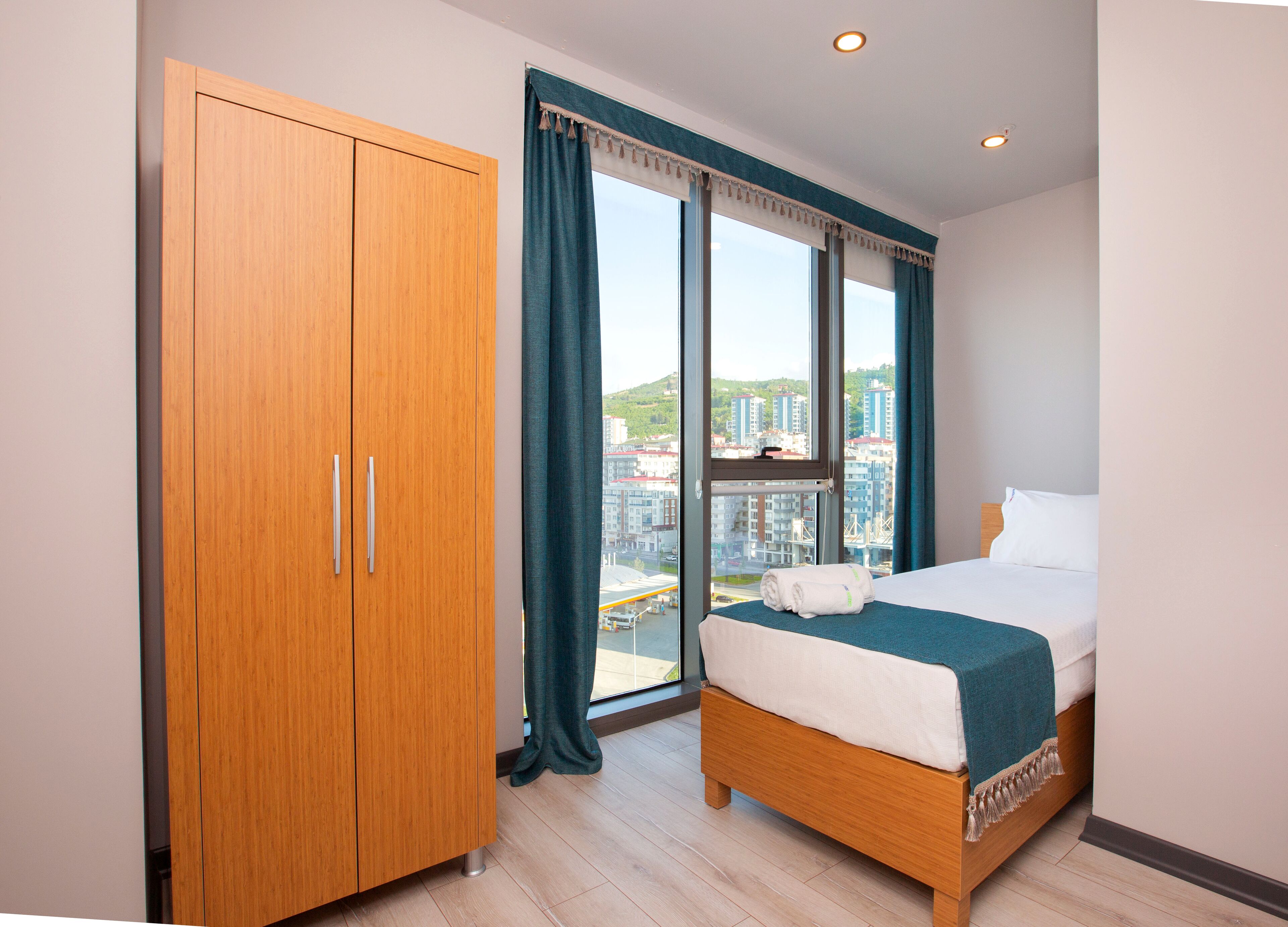 A bedroom with a large window, a bed, and a wardrobe.