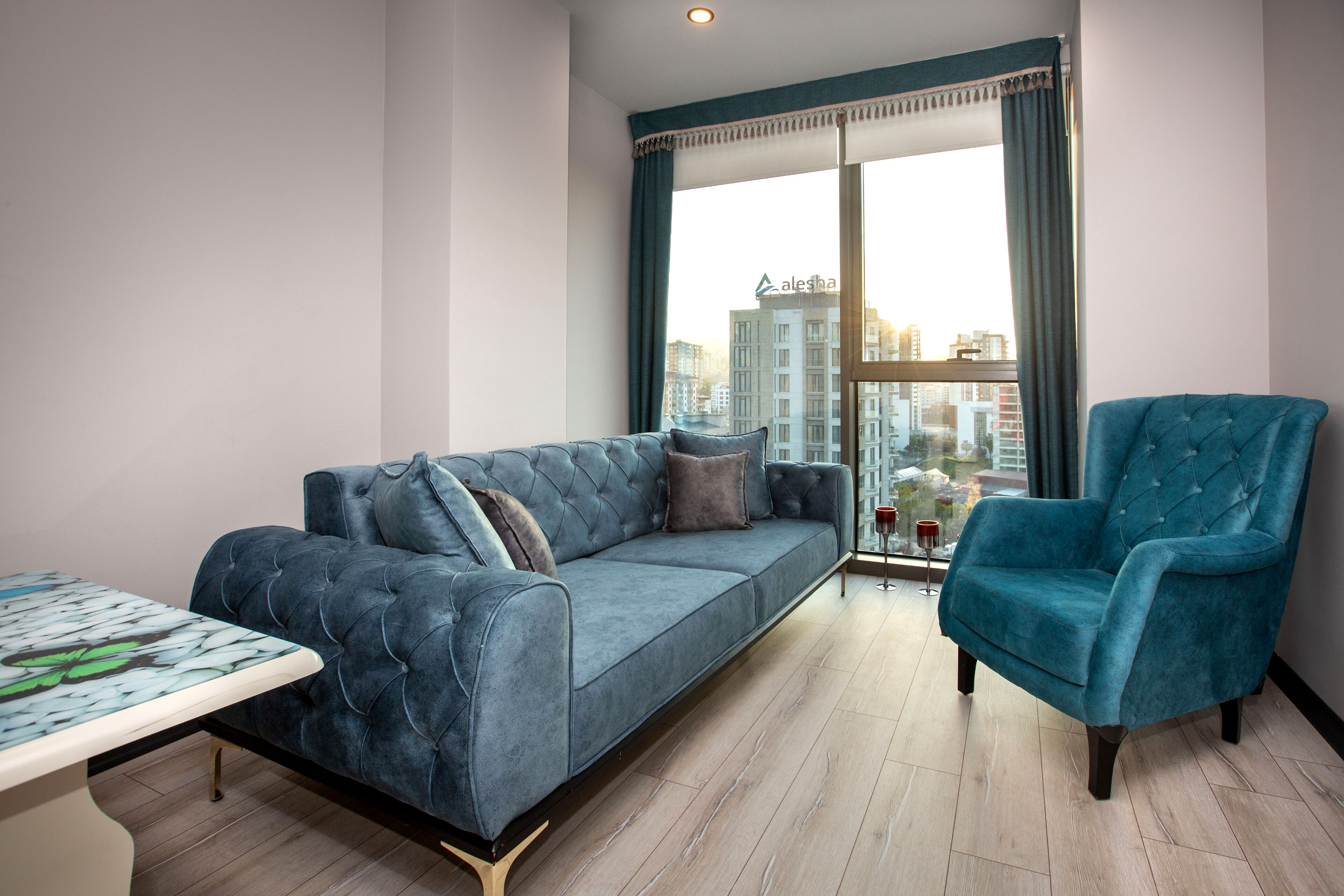 Ein modernes Wohnzimmer mit einem blauen Sofa, einem passenden Sessel und einem Esstisch.