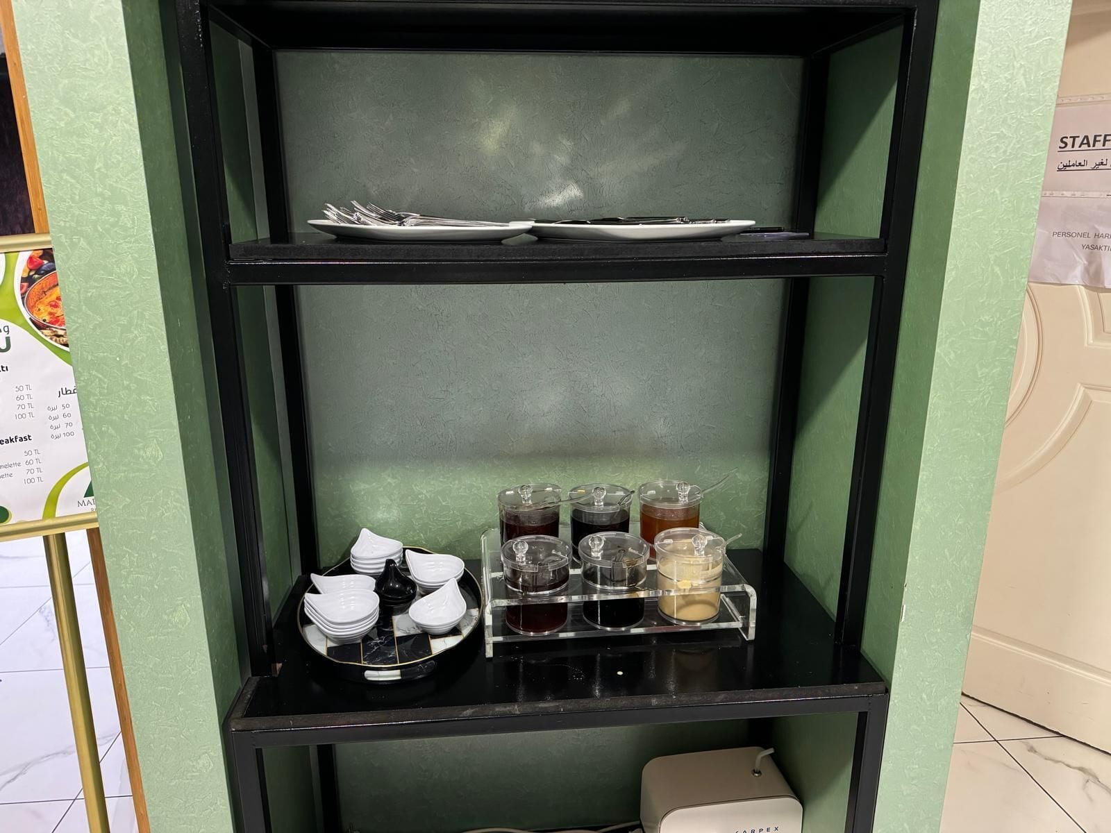 A black shelf with a plate, bowls, and condiment containers.
