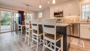 A modern kitchen with white cabinets, stainless steel appliances, and pendant lighting.