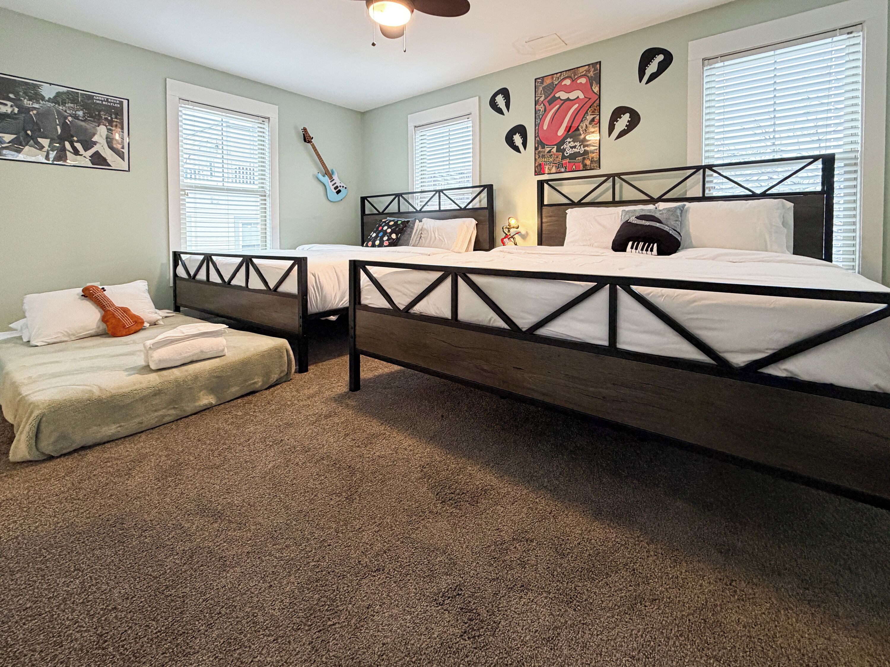A bedroom with two beds, a guitar, and a poster on the wall.