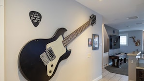 A room with a large black electric guitar mounted on the wall, a pool table, and a saxophone in the background. - Rock N Rooftop W/Skyline Views+80 in tv, Pinball, Shuffleboard and more! (Cleveland)