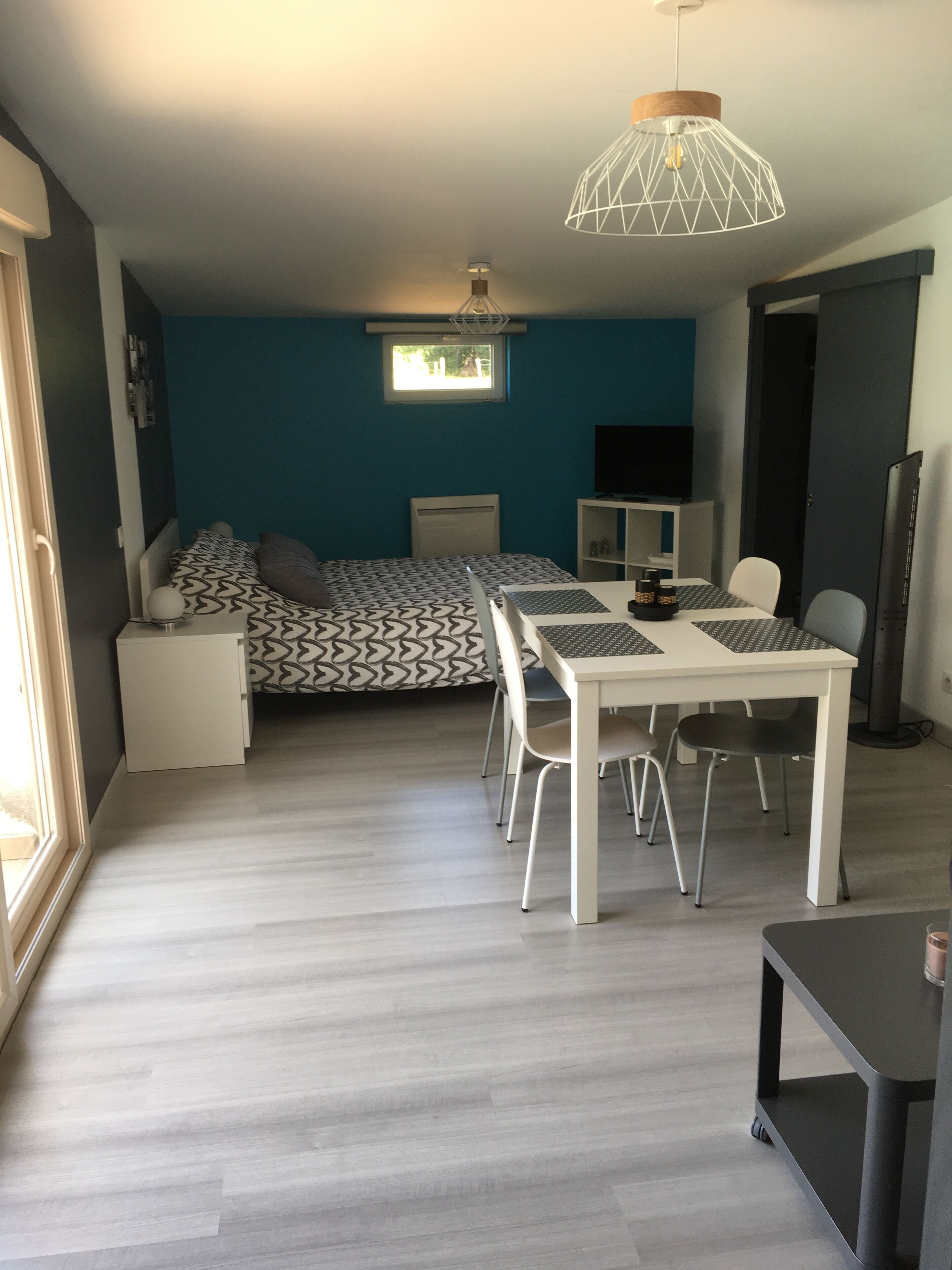 A modern room with a bed, a desk, and a dining table.