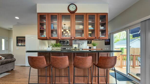 Una cocina con una isla central, armarios de madera y un reloj encima.