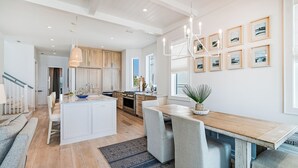 A modern kitchen with a central island, wooden cabinets, and a dining area with a bench.