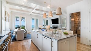 A spacious kitchen with a large island, pendant lights, and a view to the outside.