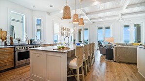 A modern kitchen with a central island, wooden flooring, and pendant lighting.