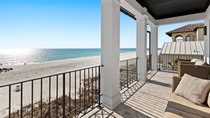 A balcony with a view of the beach and ocean.