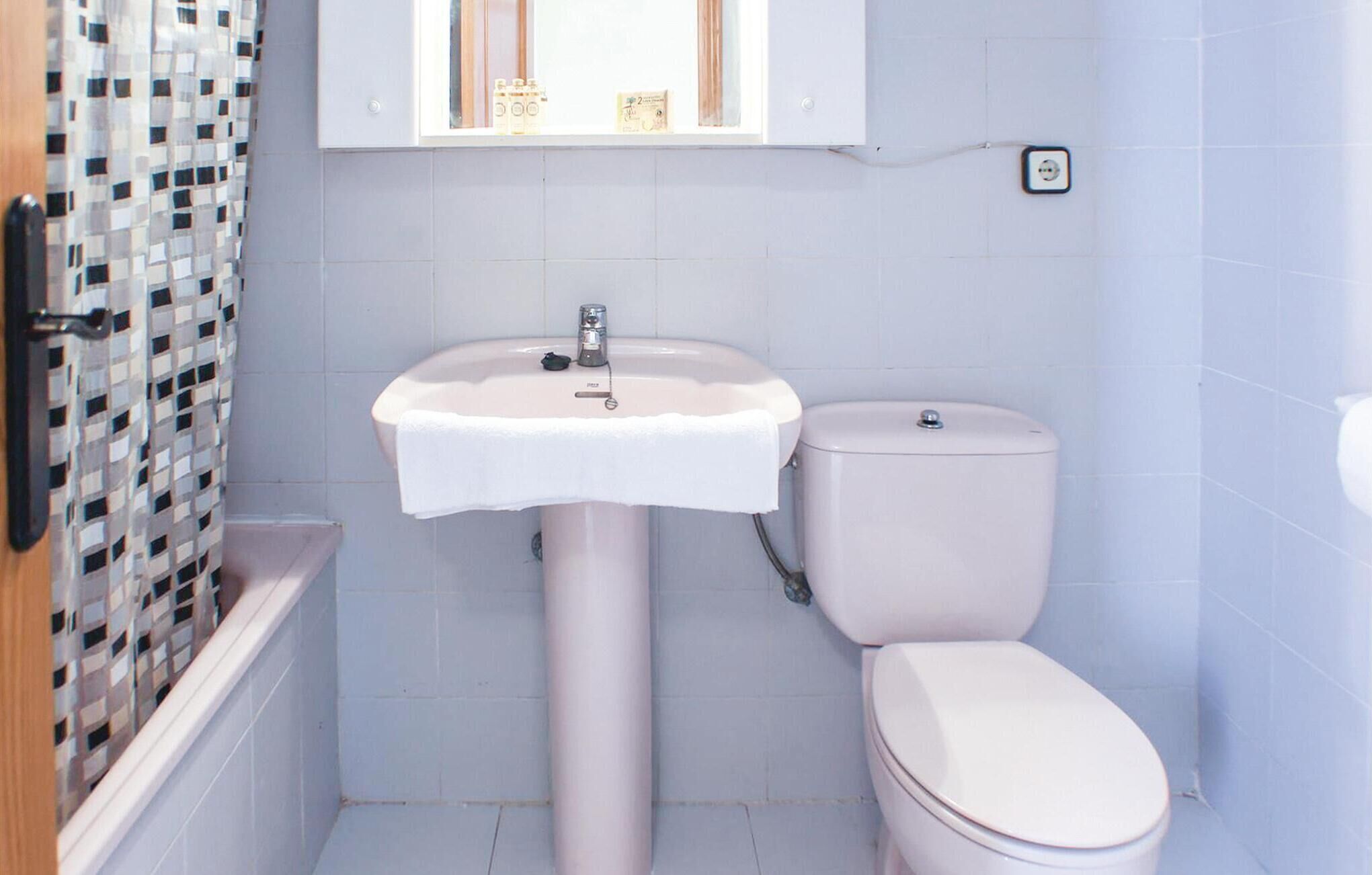 Un baño con lavamanos blanco, inodoro y paredes de azulejos.