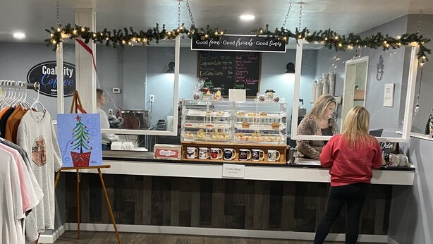 Ein Ladentresen eines Cafés mit einer Speisekarte, einer Gebetskiste und einer Auswahl an Kaffeetassen.