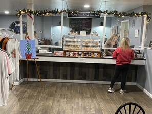 A coffee shop counter with a menu board, a prayer box, and a display of coffee mugs. - 360 Degree Mountain View (Jenkins)