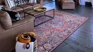 A spacious living room with leather sofas, a coffee table, and a patterned rug. - The Red Farmhouse (Ferndale)