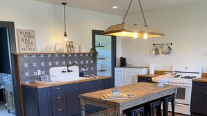 A modern kitchen with dark cabinets, a wooden island, and a patterned backsplash. - The Red Farmhouse (Ferndale)