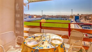 Un balcone con tavolo apparecchiato per mangiare, con vista su un campo sportivo e una zona residenziale.