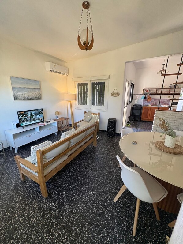 A compact living space with a sofa, a dining table, a TV, and a kitchen area. - House Piriápolis Residential area beach 3 blocks (Piriápolis)