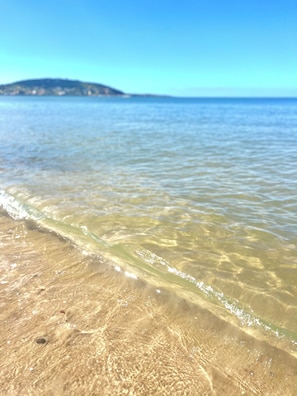 A beach with clear shallow water and a distant landmass. - House Piriápolis Residential area beach 3 blocks (Piriápolis)