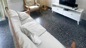 Una habitación con sofá, televisión sobre un mueble, lámpara y un cuadro en la pared.
